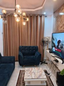a living room with a couch and a tv at Modern & Cheerful 2 Bedroom Villa, Alagbaka in Akure