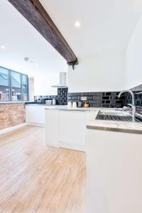 a kitchen with white cabinets and a wooden floor at Characterful 1 Bed Apartment in Burton-on-Trent in Burton upon Trent