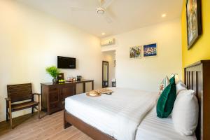 a bedroom with a bed and a chair and a television at Villa Ohana Gadren by Cocoviet Hoi An in Hoi An