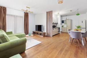 a living room with a green couch and a kitchen at PEAK Aparthotel - Old Town - by CityHost in Braşov