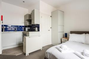 a bedroom with a white bed and a kitchen at Modern and Cosy Budget Studio in Central Doncaster in Doncaster