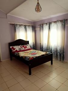 a bedroom with a bed in front of windows at Nick's and Essy's place in Juja