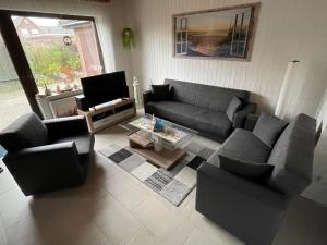 a living room with a couch and chairs and a tv at Ferienhaus Gomann in Dornum