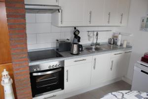 a kitchen with white cabinets and a stove top oven at Ferienhaus Gomann in Dornum +19 photos