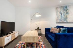 a living room with a blue couch and a tv at Modern Budget Apartment in Central Doncaster in Doncaster