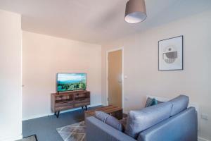 uma sala de estar com um sofá azul e uma televisão em Contemporary 1 Bed Manchester Apartment em Manchester
