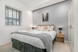 a white bedroom with a large bed and a window at Stylish 1 Bedroom Apartment in Central Woking in Woking