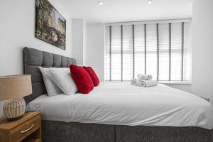 a bedroom with a large white bed with red pillows at Modern 2 Bedroom Apartment in Central Woking in Woking