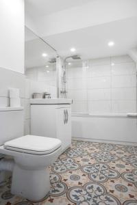 a white bathroom with a toilet and a tub at Modern 2 Bedroom Apartment in Central Woking in Woking