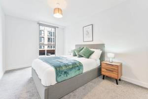 a white bedroom with a large bed and a night stand at Central Birmingham 1 Bedroom Apartment in Birmingham