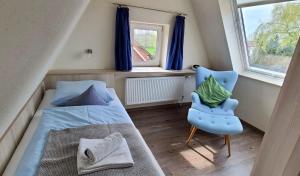 ein Schlafzimmer mit einem Bett, einem Stuhl und einem Fenster in der Unterkunft GRÜNBLAU RELAX Pension & Apartments in Warnemünde