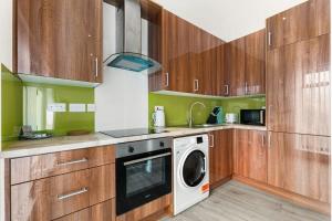 cocina con armarios de madera, lavadora y secadora en Lovely 1 Bedroom Apartment in Woking Centre, en Woking