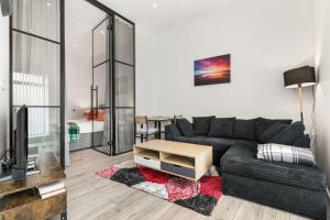 a living room with a black couch and a tv at Lovely 1 Bedroom Apartment in Woking Centre in Woking