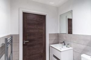 a bathroom with a sink and a wooden door at Bright & Modern 1 Bed Apartment by Old Trafford in Manchester