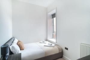 een witte slaapkamer met een bed en een raam bij Spacious 3 Bed Apartment in Waterloo Liverpool in Waterloo