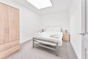 a white bedroom with a bed and a wooden cabinet at Modern and Bright 1 Bed Apartment in Dudley in Brierley Hill