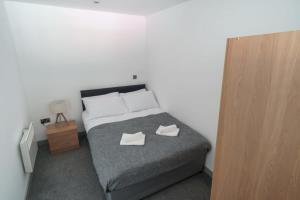 Cosy 1 Bed Apartment in Central Blackburn في بلاكبيرن: غرفة نوم عليها سرير وعليها حذان ابيض