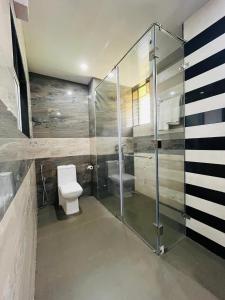 La salle de bains est pourvue de toilettes et d'une douche en verre. dans l'établissement Tattvam Wild Ocean, à Arambol