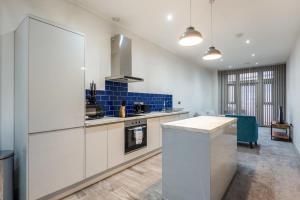 a large kitchen with white cabinets and blue tiles at Budget 1 Bed Apartment in Central Doncaster in Doncaster