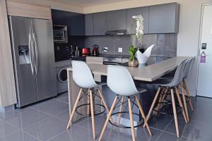 een keuken met een houten tafel en witte stoelen bij The Capital Menlyn Maine in Pretoria