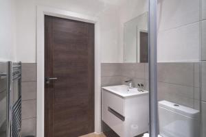 La salle de bains est pourvue d'un lavabo, de toilettes et d'une porte. dans l'établissement Lovely 1 Bedroom Apartment in Old Trafford, à Manchester