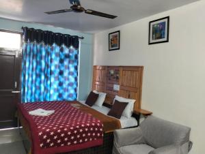 a bedroom with a bed and a chair and a window at Aman Inn in Dharamshala