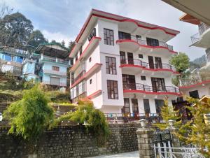 a white building with balconies on top of a wall at Aman Inn in Dharamshala