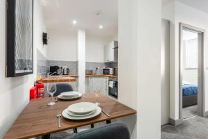 Smart 1 Bedroom Apartment in Leeds في ليدز: مطبخ وغرفة طعام مع طاولة وكراسي خشبية