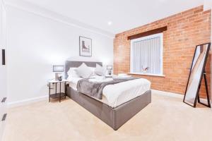 特倫特河畔伯頓的住宿－Spacious 2 Bed Apartment in Burton-on-Trent，一间卧室设有一张大床和砖墙