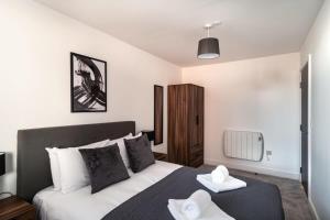 Modern & Spacious 2 Bed Apartment by Old Trafford في مانشستر: غرفة نوم عليها سرير وفوط