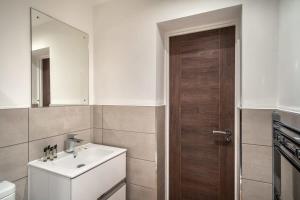 a bathroom with a sink and a wooden door at Modern & Spacious 2 Bed Apartment by Old Trafford in Manchester
