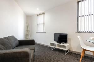 a living room with a couch and a tv and a table at Contemporary 1 Bed Budget Flat in Central Halifax in Halifax