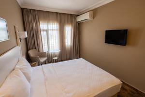 a hotel room with a bed and a flat screen tv at Olbios Marina Resort Hotel in Kumkuyu