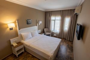 a hotel room with a bed and a television at Olbios Marina Resort Hotel in Kumkuyu