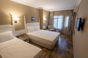 a hotel room with two beds and a television at Olbios Marina Resort Hotel in Kumkuyu