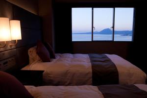 Grand Mercure Beppu Bay Resort & Spa في بيبو: غرفة نوم بسريرين ونافذة كبيرة