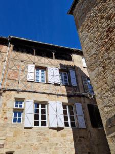 un edificio alto de ladrillo con ventanas blancas. en Maison Ambre, en Figeac