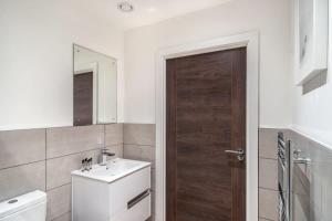 a bathroom with a sink and a wooden door at Lovely Modern 1 Bed Apartment by Old Trafford in Manchester
