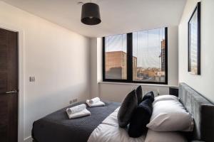 a bedroom with a bed with pillows and two windows at Modern & Spacious 1 Bed Apartment - Old Trafford in Manchester