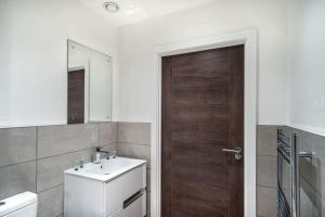 a bathroom with a sink and a wooden door at Modern & Spacious 1 Bed Apartment - Old Trafford in Manchester