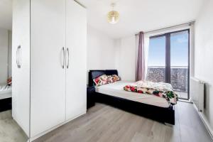 um quarto com uma cama e uma grande janela em Smart 1 Bedroom Apartment in Canning Town em Londres