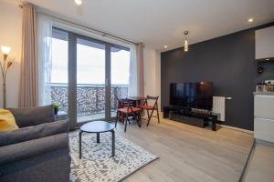 uma sala de estar com um sofá, uma mesa e uma televisão em Smart 1 Bedroom Apartment in Canning Town em Londres