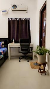 a desk and a chair in a room with a window at Ruchika's Orchid in Hyderabad