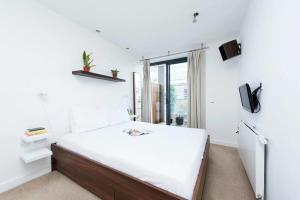 1 dormitorio con 1 cama grande con sábanas blancas en Modern 2 Bed Apartment w Balcony in London en Londres