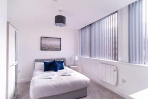 a white bedroom with a large bed with blue pillows at Spacious 1 Bed Old Trafford Apartment in Manchester