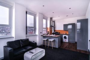 Contemporary 1 Bed Apartment in Central Blackburn في بلاكبيرن: غرفة معيشة مع أريكة سوداء ومطبخ
