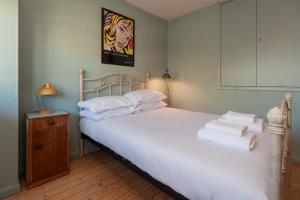 um quarto com uma cama com lençóis brancos e almofadas em Centrally Located 4 Bedroom London Apartment em Londres