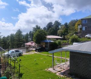 Blick auf einen Hof mit einem Haus und einem Auto in der Unterkunft The Teal Cottage in Murree