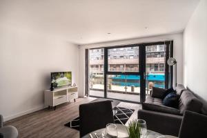 Stunning 2 Bed Apartment in Central Manchester في مانشستر: غرفة معيشة مع أريكة ونافذة كبيرة