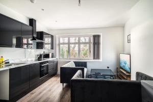 a kitchen with black cabinets and a living room at Spacious 2 Bed Apartment in Waterloo Liverpool in Waterloo +7 photos